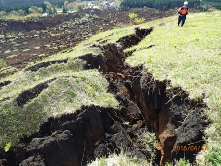 平成28年熊本地震により引き起こされた土砂災害による行方不明者の捜索救助活動現場（写真上部中央）に対する二次災害の危険性を評価するため、崩れた崖の周辺の地形と地質を調査している様子